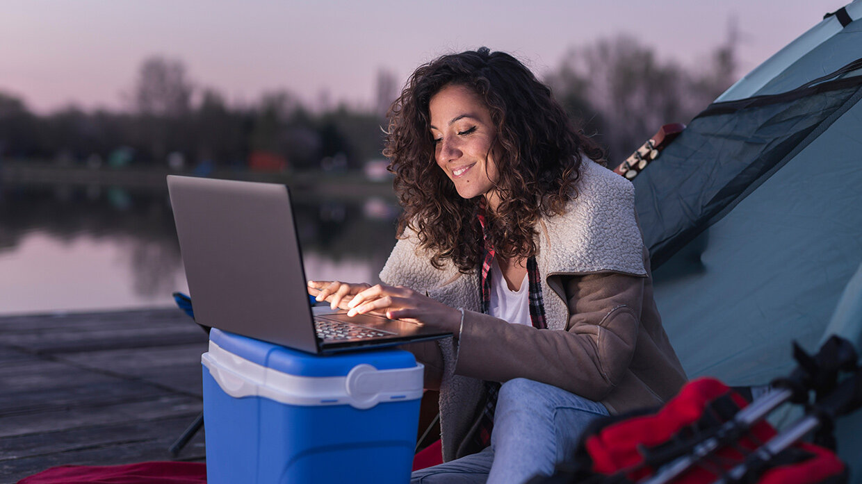 Jeune femme utilisant un ordinateur portable lors d'un bivouac